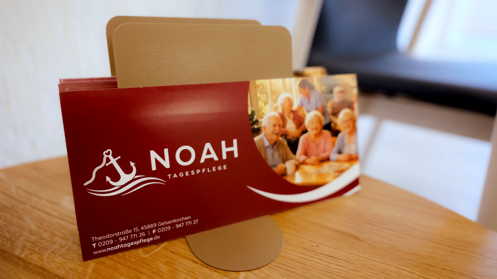 Infoflyer der NOAH Tagespflege im Holzaufsteller auf einem Tisch.